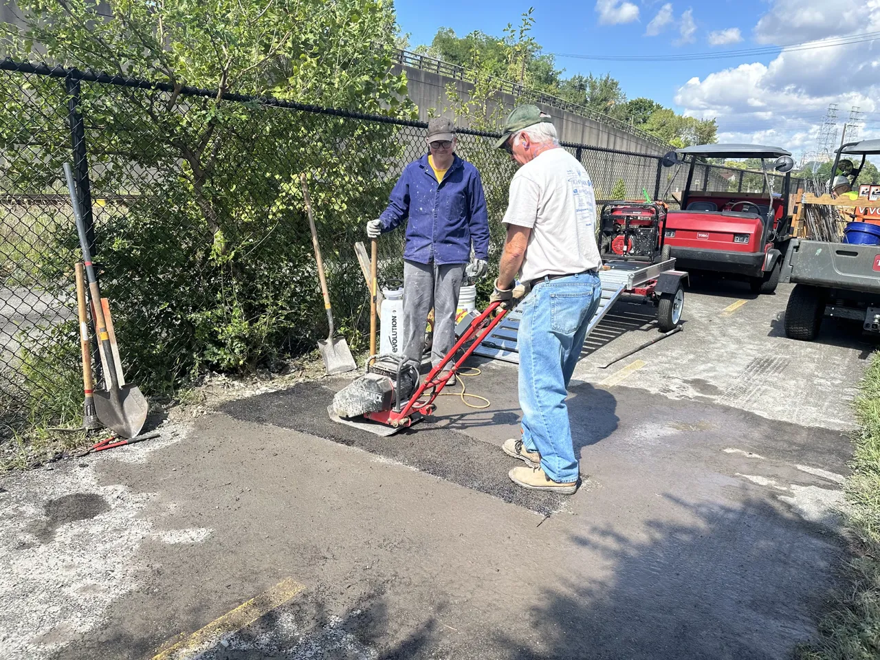 Two volunteers resurfacing the path with a plate compactor and shovels on the Steel Valley Trail
